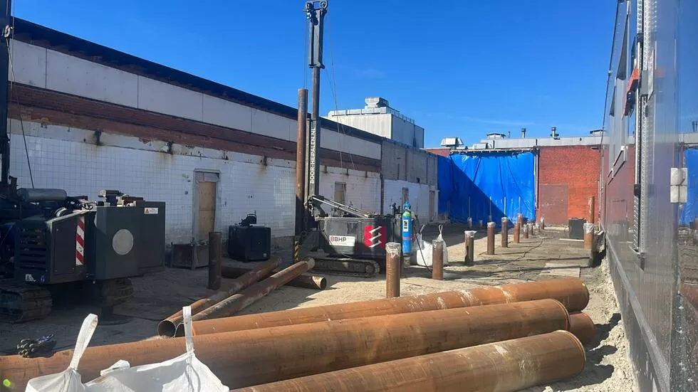 Gründungsarbeiten auf Baustelle mit Holzbalken und Baumaschinen für Fundamentarbeiten