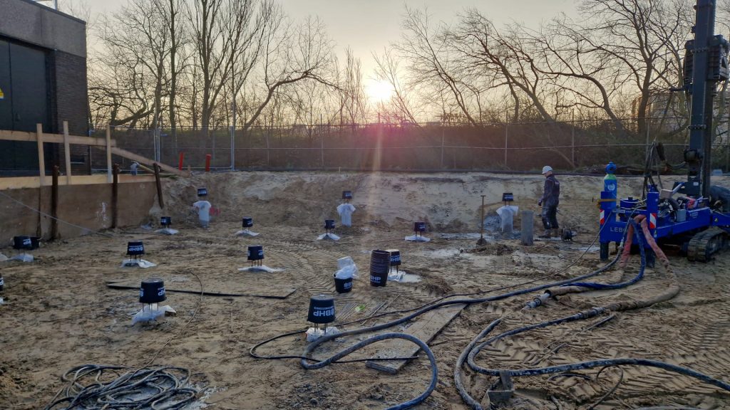 Bohrpfahlgründung im Bau mit Bewehrungskörben und Baumaschinen auf der Baustelle bei Sonnenuntergang