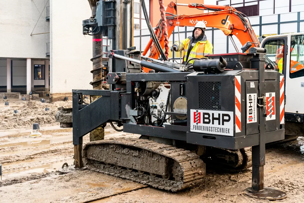 Bohrgerät auf Raupenfahrwerk führt Pfahlgründungsarbeiten auf städtischer Baustelle durch
